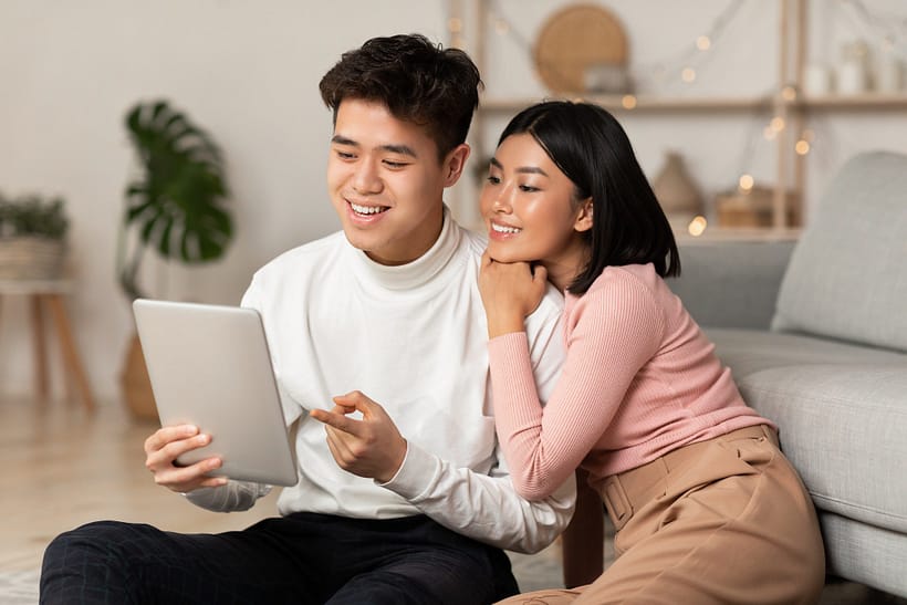 young-asian-spouses-relaxing-using-digital-tablet-browsing-internet-indoors.jpg